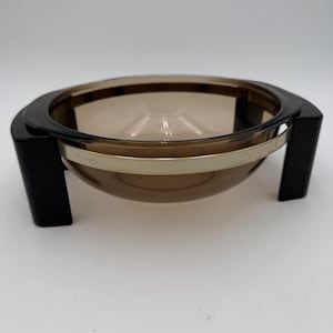 Peut inclure: Une tasse en céramique blanche avec une anse noire et l'inscription "But First, Coffee" en gras noir. La tasse est posée sur un fond flou. La tasse mesure environ 10 cm de hauteur.