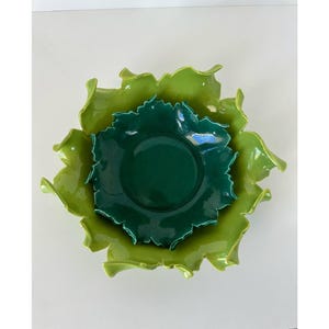 Puede incluir: Tres cuencos de cerámica en tonos verdes, anidados. El cuenco más grande es de un verde brillante y frondoso con un borde ondulado. El cuenco del medio es de un verde bosque más oscuro con un borde festoneado. El cuenco más pequeño es de un verde intenso.