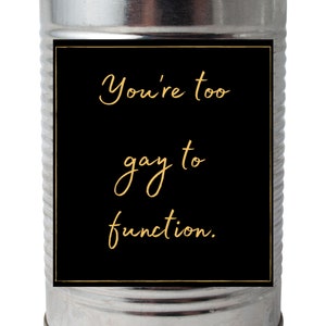 Peut inclure: Une boîte métallique argentée avec une étiquette noire. L'étiquette porte le texte doré "You're too gay to function."