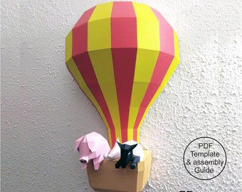 May include: A papercraft hot air balloon with red and yellow stripes, carrying a pink pig and a black and white cow. The balloon is suspended in the air, and the animals are sitting in a brown basket. The text "PDF Template & assembly Guide" is visible in the lower right corner of the image. The text "FP Design Crafts" is visible in the lower right corner of the image.