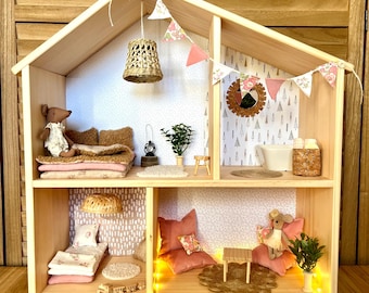 May include: A wooden dollhouse with two stories and multiple rooms, furnished with miniature beds, pillows, and decorative items. The dollhouse is decorated with pink and floral accents, and includes a small mouse doll.