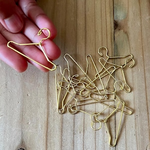 K&ouml;nnte beinhalten: Ein Haufen kleiner goldfarbener Metallb&uuml;gel. Die B&uuml;gel sind etwa so gro&szlig; wie ein Fingernagel.