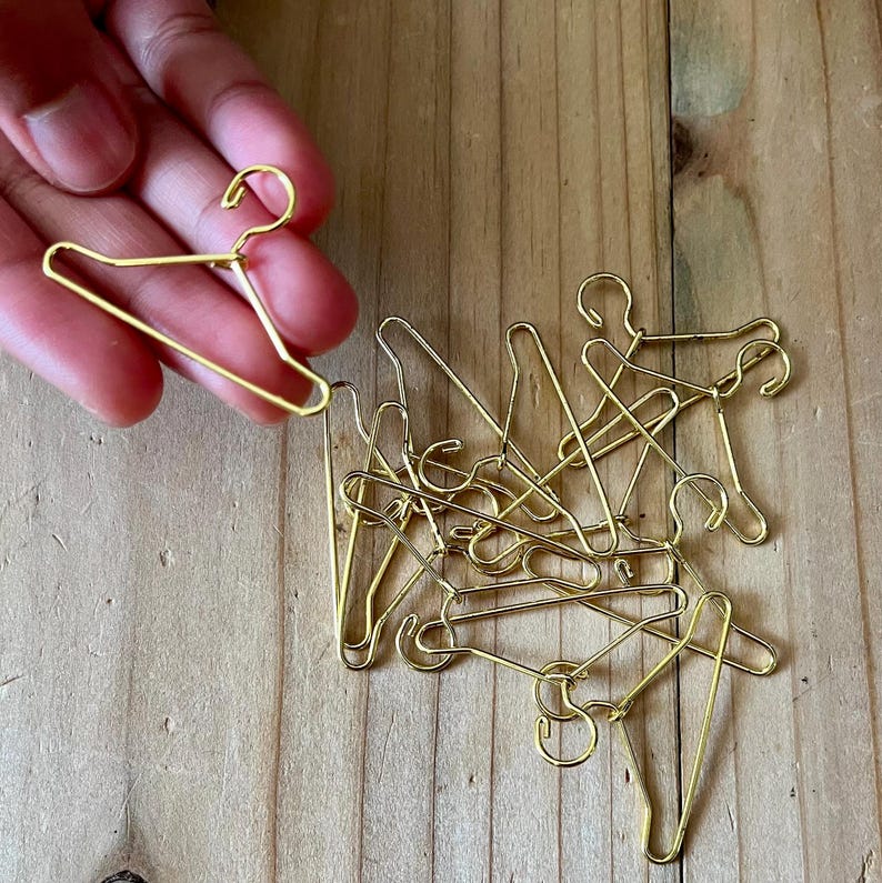 K&ouml;nnte beinhalten: Ein Haufen kleiner goldfarbener Metallb&uuml;gel. Die B&uuml;gel sind etwa so gro&szlig; wie ein Fingernagel.