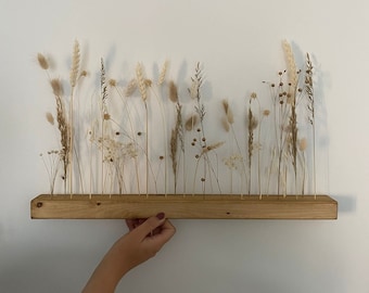 May include: A wooden shelf with a row of dried grasses and flowers in various shades of brown and beige.