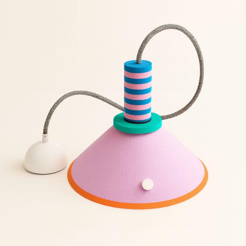 Op de afbeelding: Een hanglamp met een grote, getextureerde lichtroze conische kap met een oranje rand en een klein wit rond accent. De bovenkant heeft een groenblauwe ring en een cilindrische steel met horizontale blauwe en roze strepen, verbonden met een zwart-wit snoer.