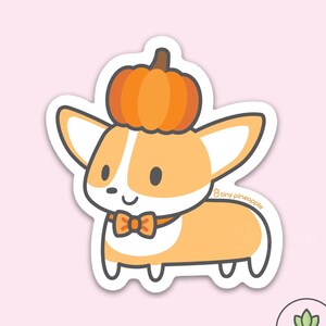 May include: A cute cartoon corgi wearing a pumpkin hat and a bow tie. The corgi is orange and white with black eyes and a black nose. The pumpkin is orange and has a green stem. The bow tie is orange and has a white bow. The background is pink.
