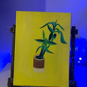Op de afbeelding: Een schilderij van een groene plant in een bruine en witte pot op een gele achtergrond.