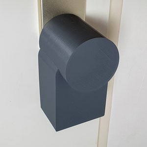 Op de afbeelding: Een donkergrijze plastic stopcontact afdekking met een afgeronde bovenkant en een rechthoekige basis.