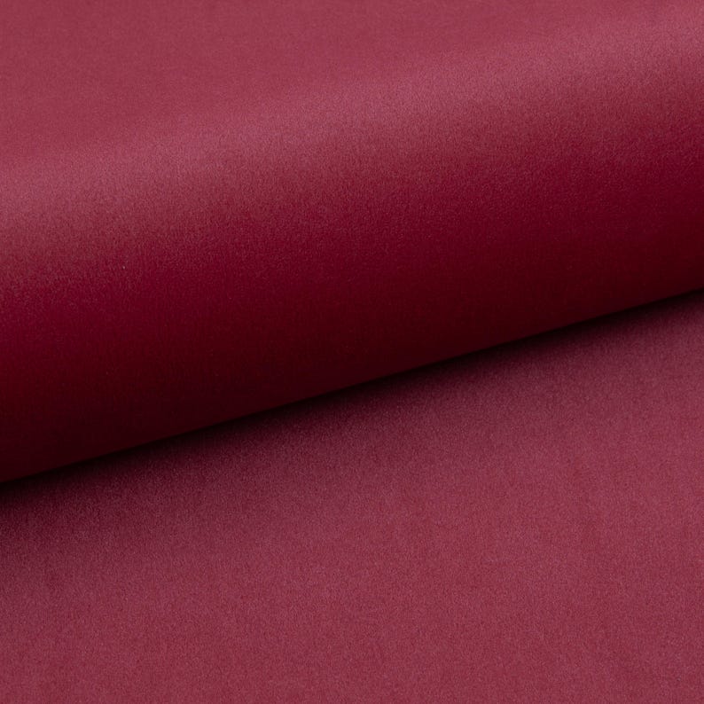 May include: A close-up of a deep burgundy fabric with a soft, velvety texture.