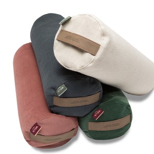 May include: Four yoga bolsters in different colors: red, dark green, dark gray, and cream. Each bolster has a brown leather strap with the word "Yogibo" printed on it.