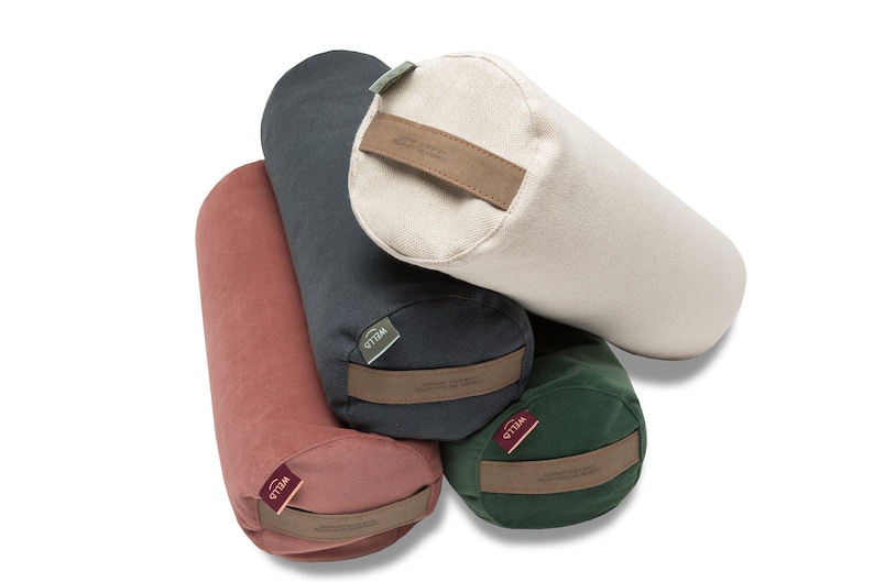 May include: Four yoga bolsters in different colors: red, dark green, dark gray, and cream. Each bolster has a brown leather strap with the word "Yogibo" printed on it.