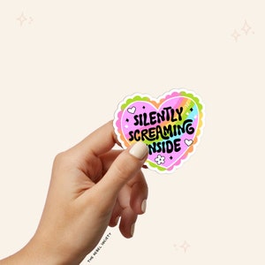 May include: A pink heart-shaped sticker with a rainbow design and the text "SILENTLY SCREAMING INSIDE".