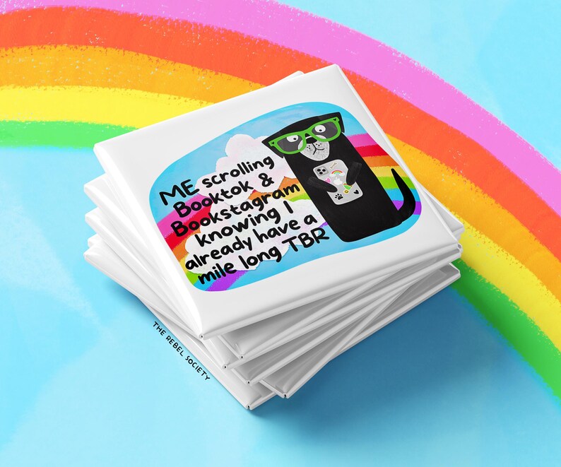 May include: A stack of white square magnets with a colorful illustration of a black otter wearing glasses and holding a phone. Text on the magnet reads "ME scrolling Booktok & Bookstagram knowing I already have a mile long TBR."