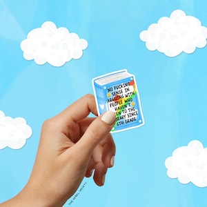 May include: A blue sticker in the shape of a book with the text "NO FUCKING SENSE IN ARGUING WITH PEOPLE WHO HAVEN'T BEEN TO THE LIBRARY SINCE 6TH GRADE." The sticker is held in a hand against a blue sky background with white cloud cutouts.