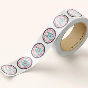 May include: A roll of white stickers with a pink and teal design. Each sticker features a shopping bag with a heart and the text "SMALL BUSINESS SUPPORT CLUB". The roll's core has the text "THE REBEL SOCIETY".