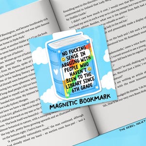 May include: A magnetic bookmark with a blue book design and the text "NO FUCKING SENSE IN ARGUING WITH PEOPLE WHO HAVEN'T BEEN TO THE LIBRARY SINCE 6TH GRADE." The bookmark is on a book.