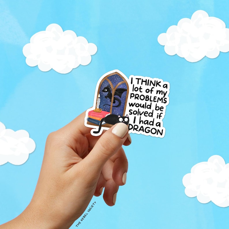 K&ouml;nnte beinhalten: Ein Aufkleber mit einem skurrilen Design mit einer schwarzen Katze, einem Drachen und dem Text "I think a lot of my problems would be solved if I had a dragon." Der Aufkleber hat einen blauen Hintergrund mit wei&szlig;en Wolken.