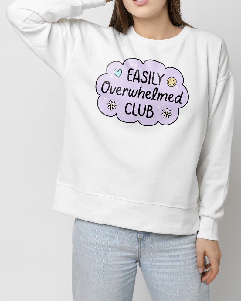 May include: White sweatshirt with a purple cloud graphic that says "EASILY Overwhelmed CLUB" with a heart, smiley face, and flowers.