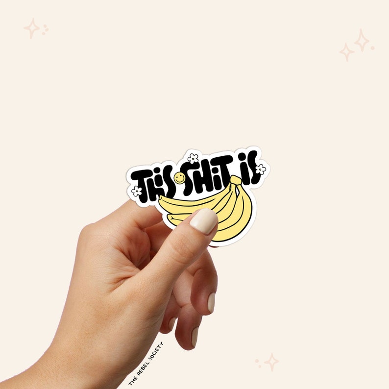 Puede incluir: Una pegatina negra y amarilla con el texto "This Shit Is" en una fuente divertida, con un racimo de pl&aacute;tanos amarillos y una carita sonriente.