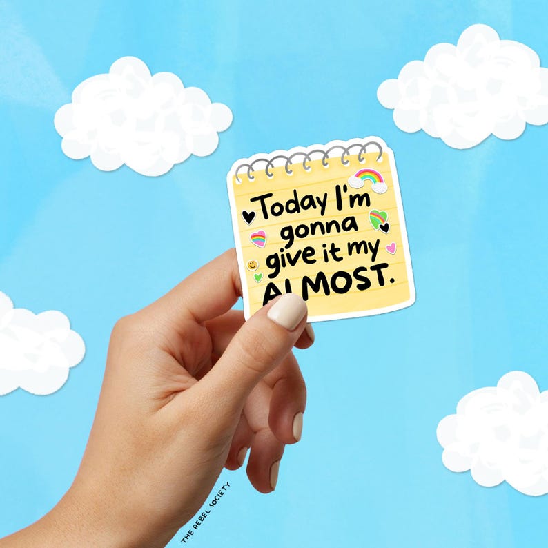 May include: A yellow sticky note with the text "Today I'm gonna give it my ALMOST" held against a blue sky background with white clouds. The note has a rainbow, hearts, and other small graphics. The words are in black.