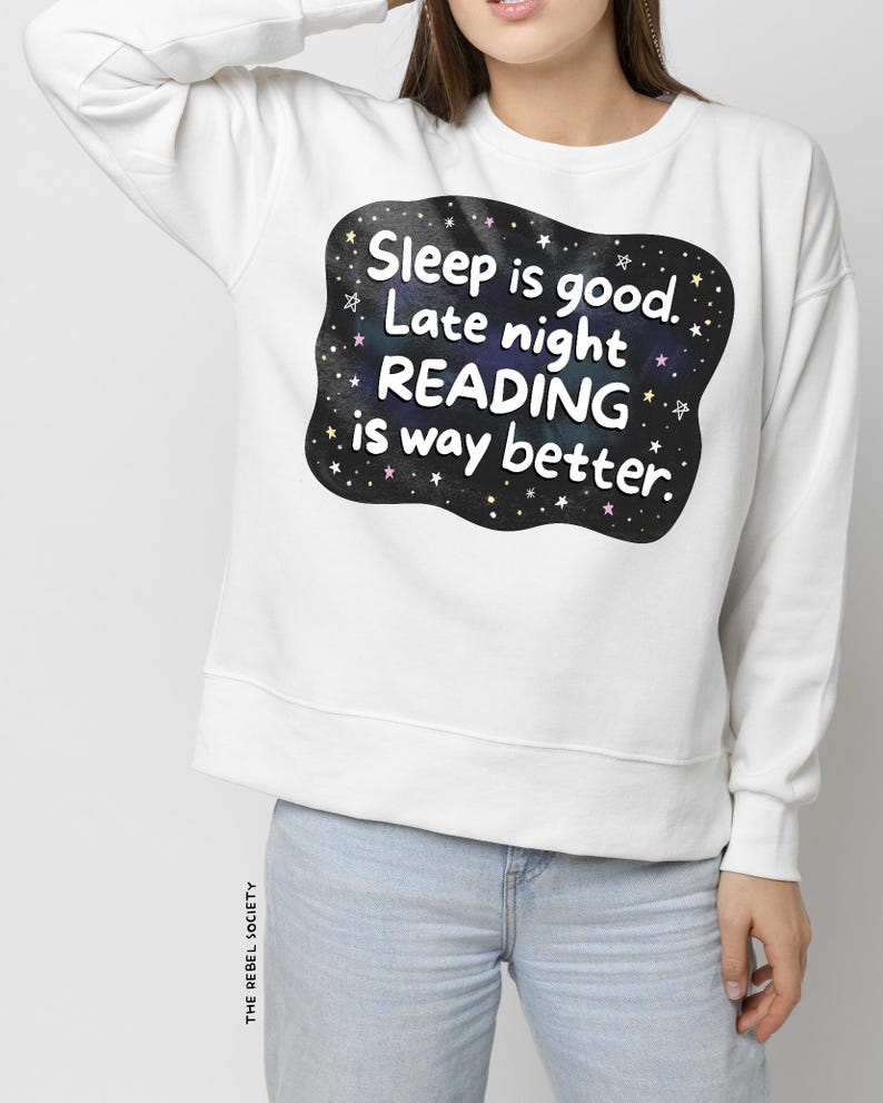 Pu&ograve; includere: Felpa bianca con grafica nera che recita "Sleep is good. Late night READING is way better." La grafica presenta un design a cielo stellato. La felpa &egrave; abbinata a jeans azzurri.