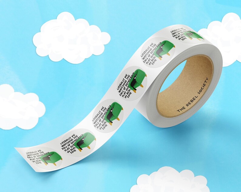 May include: A roll of white, round stickers with a cartoon image of a green chair and the text "Literally me watching the fall of democracy play out in real time." The roll has a brown cardboard core and the text "The Rebel Society."