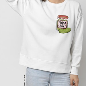 May include: White sweatshirt with a cartoon illustration of a pickle jar with the text "Pickle Hoe" on the front.