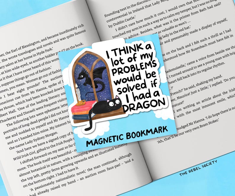 K&ouml;nnte beinhalten: Magnetischer Lesezeichen mit dem Text "I THINK a lot of my PROBLEMS would be solved if I had a DRAGON." Das Lesezeichen zeigt einen Drachen, eine schwarze Katze und ein Fensterdesign.