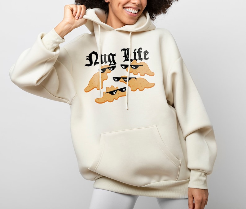 May include: A cream-colored hoodie with a black graphic of chicken nuggets wearing sunglasses and the text "Nug Life".