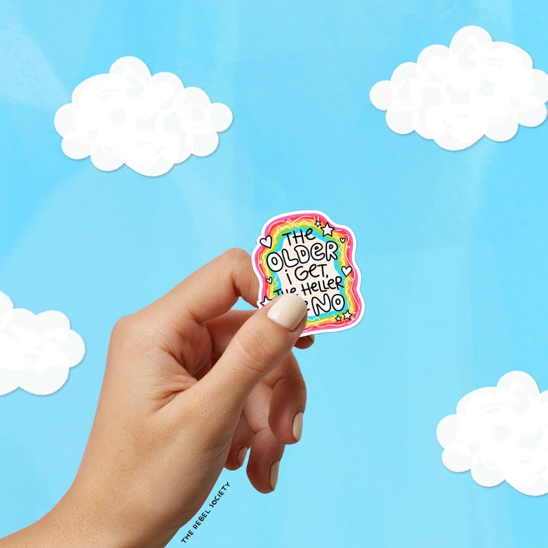 May include: A die-cut sticker featuring a rainbow-colored border with small white hearts and stars. The text in the center reads, THE OLDER I GET, THE HELLER THE NO, written in a bold, black, hand-lettered font against a white background.