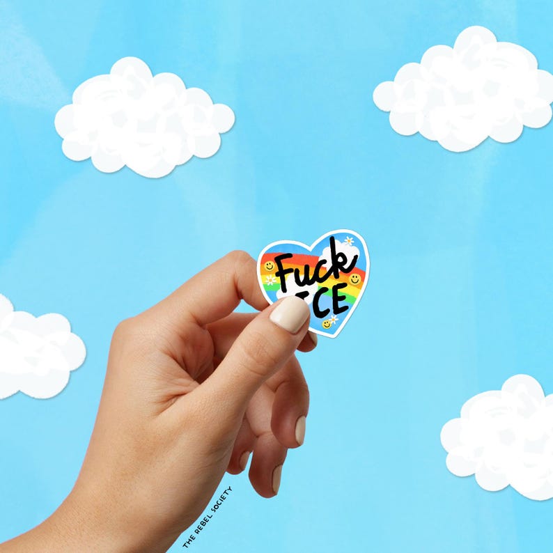 K&ouml;nnte beinhalten: Ein herzf&ouml;rmiger Aufkleber mit den Worten "Fuck ICE" in Schwarz und Regenbogenfarben. Der Aufkleber hat einen blauen Hintergrund mit einem Regenbogen und Smiley-Gesichtern. Der Aufkleber wird vor einem blauen Himmel mit wei&szlig;en Wolken gehalten.