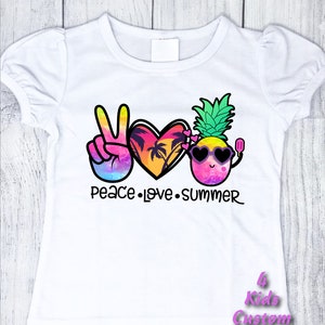 May include: White t-shirt with a peace sign, heart, and pineapple graphic. The graphic is colorful and features a sunset, palm trees, sunglasses, and a popsicle. The text "Peace Love Summer" is printed below the graphic.