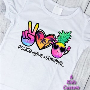 May include: White t-shirt with a colorful peace sign, heart, and pineapple design. The text "peace love summer" is written below the design.