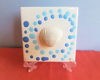 Weiße Muschel mit hellblauem und metallischem blauem Polka-Dot-Swirl-Design auf einer 4-Zoll-Fliese