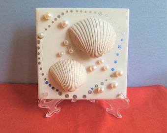 Weiße Muscheln und Perlen in metallischem Silber und blau bemaltem Polka-Dot-Kreis auf einer 4 "x 4" -Fliese