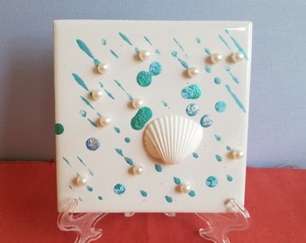 Weiße Muschel mit Regentropfen aus Metallic Blau, Türkis und Silber bemalte Tupfen auf einer 10 x 10 cm Fliese