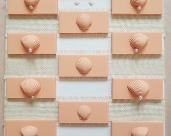 Schlichte Eleganz: Leinwand mit Pfirsichmuscheln und Perlen auf schwarzen Fliesen