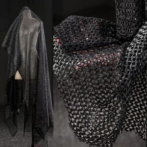 Puede incluir: Tela negra de tejido abierto con un hilo metálico brillante. La tela está drapeada sobre un maniquí y también se muestra en primer plano, revelando el intrincado patrón similar a una red. El material tiene un ligero brillo, que capta la luz.