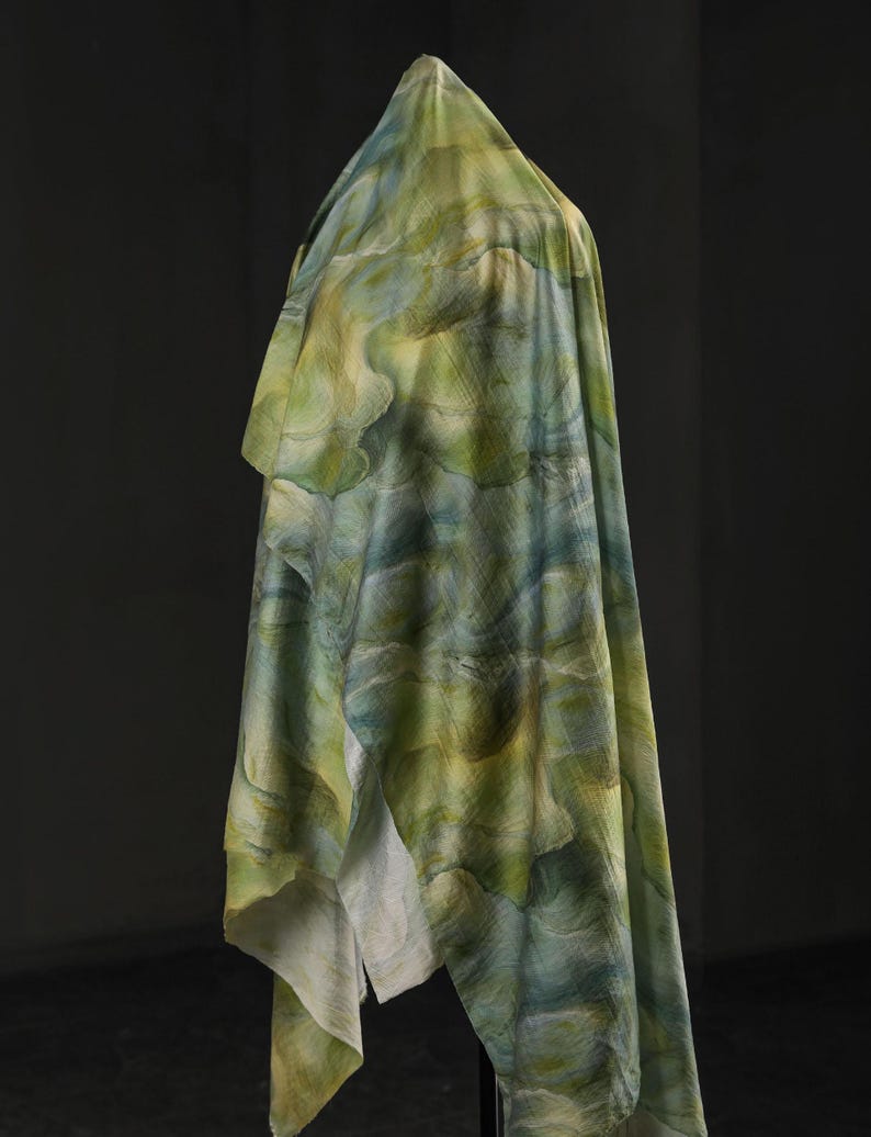 Puede incluir: Una tela drapeada con un patr&oacute;n similar a la acuarela en tonos verdes, azules y amarillos. La tela est&aacute; drapeada sobre una forma invisible, creando pliegues suaves y una apariencia fluida. El efecto general es art&iacute;stico y et&eacute;reo.