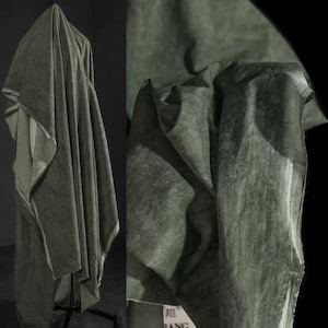 May include: A draped fabric in a muted olive green hue. The material appears soft and textured, with folds and shadows creating depth. The fabric is displayed on a mannequin, showcasing its drape and flow.