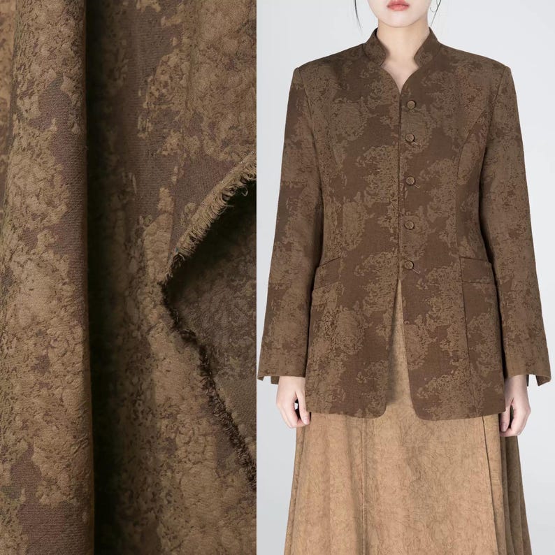 May include: A brown jacket with a floral pattern, featuring a mandarin collar and button closure. The jacket is paired with a matching brown skirt. The image also shows a close-up of the fabric, revealing its texture and color.