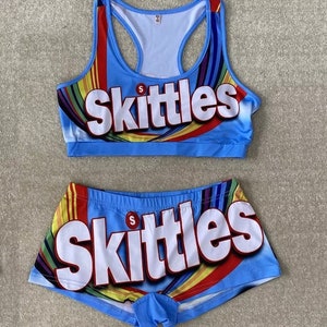 May include: A blue and white two-piece set with a rainbow design and the word "Skittles" printed on it.