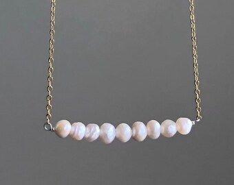 May include: A delicate gold chain necklace with a row of small white pearls.