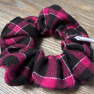 Peut inclure: Un chouchou à carreaux noirs et roses. L'accessoire pour cheveux est en tissu doux avec des détails de couture blancs. Le chouchou est un accessoire pour cheveux.