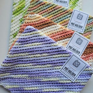 May include: Four crocheted pot holders in different colours, stacked on top of each other. Each pot holder has a white tag attached with the text "Hot Pad Pot Holder 100% Handmade".
