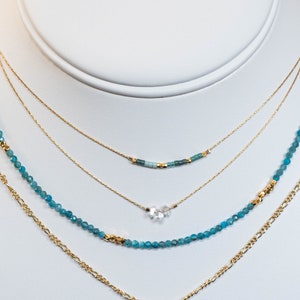 Puede incluir: Un collar de oro de varias capas con un colgante en forma de l&aacute;grima y cuentas de piedras preciosas azules. El colgante est&aacute; hecho de cuarzo transparente.