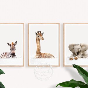 Könnte beinhalten: Set aus drei gerahmten Kunstdrucken mit Aquarellillustrationen eines Zebras, einer Giraffe und eines Elefanten. Die Tiere sind in einer weichen, neutralen Farbpalette dargestellt, ideal für ein Kinderzimmer. Jeder Druck ist in einem hellen Holzrahmen.