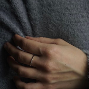 May include: A delicate gold band ring with small, clear gemstones set in a row.