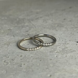 May include: Two thin gold wedding bands with a row of small diamonds on one band.