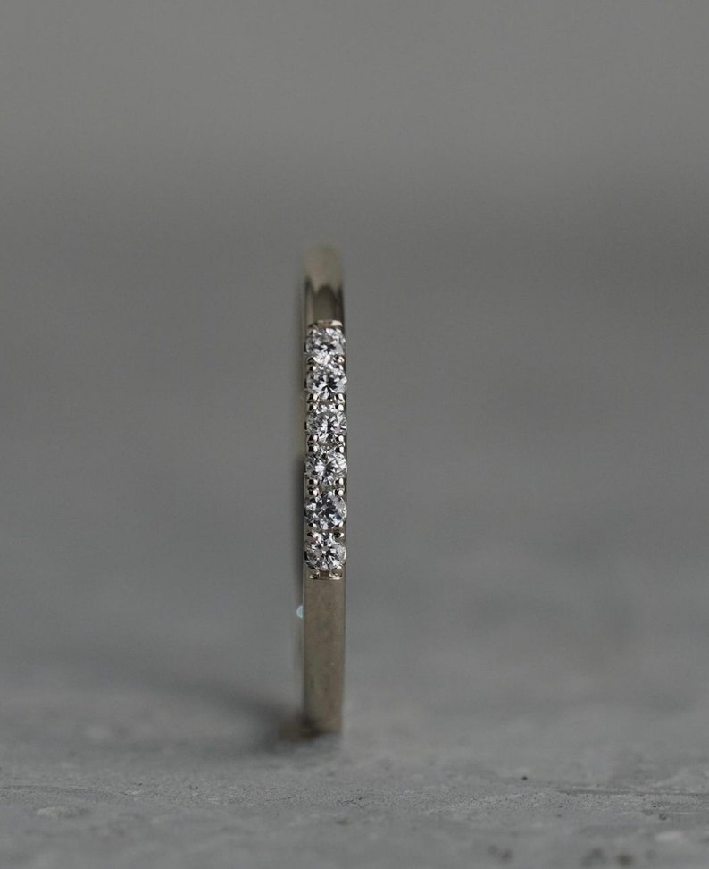 May include: A thin silver band with a row of small diamonds set into the metal.